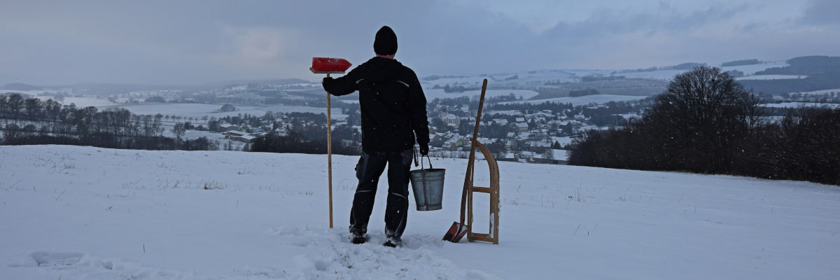 Marek, der Wintermacher – steht mit Schlitten, Besen und Eimer auf der Bergkuppe, bereit, den Winter zu starten