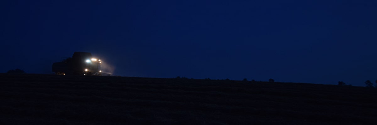 Cosechadora trabajando de noche bajo intensos focos