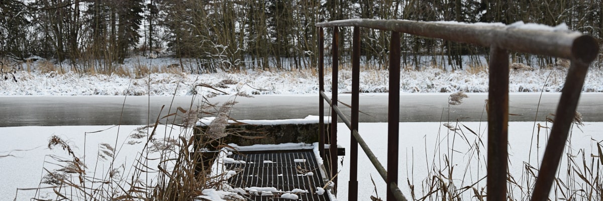 Teich im Winter – Schnee und Eis, kleiner Steg ragt in den Teich